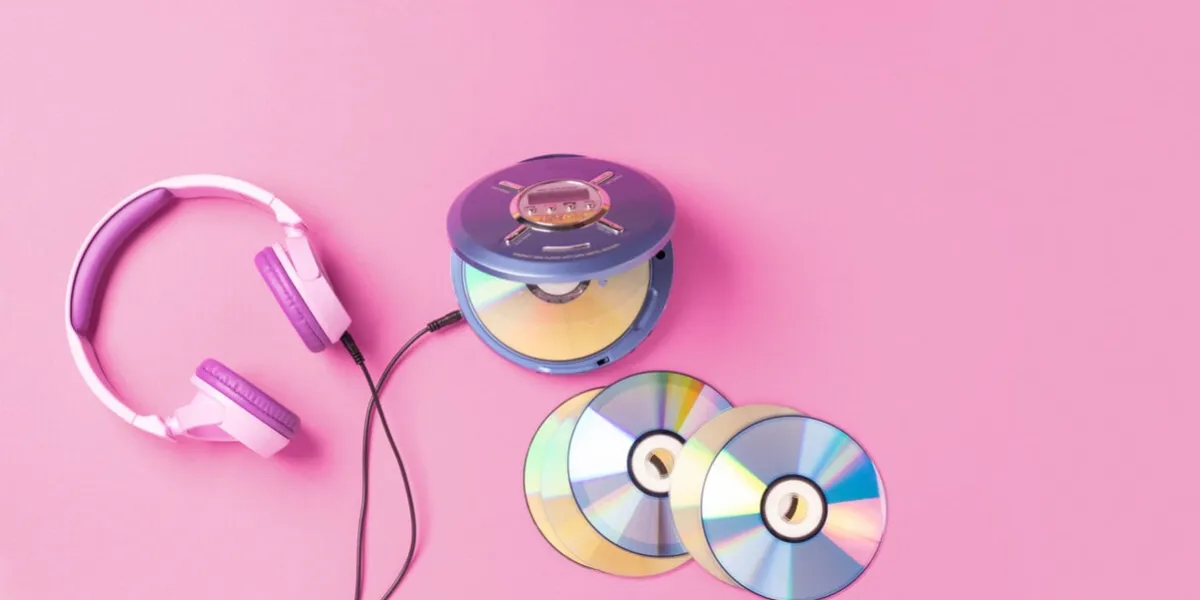 personal compact portable cd player disks purple headphones on a pink background top view layout, copy space, place for text or advertising hobby entertainment leisure