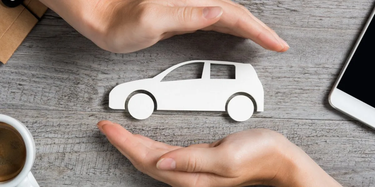 hands protecting icon of car over wooden table top view of hands showing gesture of protecting car car insurance and automotive business concept