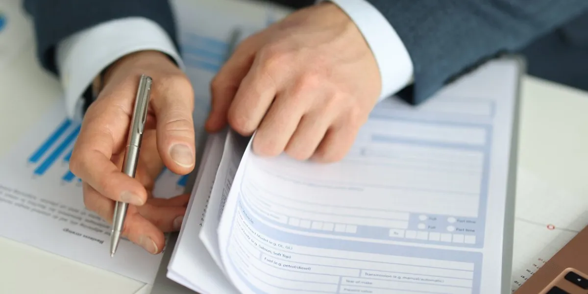 businessman holds pen and stretches application form signing insurance documents concept