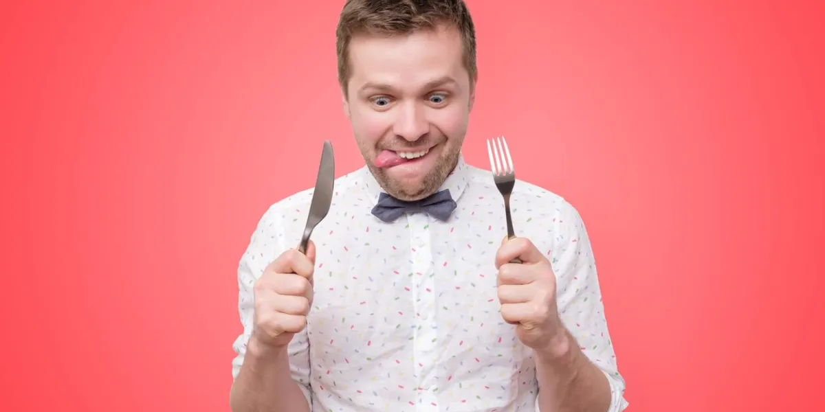 hungry young man holding fork and knife on hand ready to eat, licking lips diet and healthy food concept