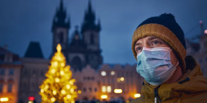 young man with face mask against christmas tree in prague themes coronavirus pandemic during christmas holiday and personal responsibility