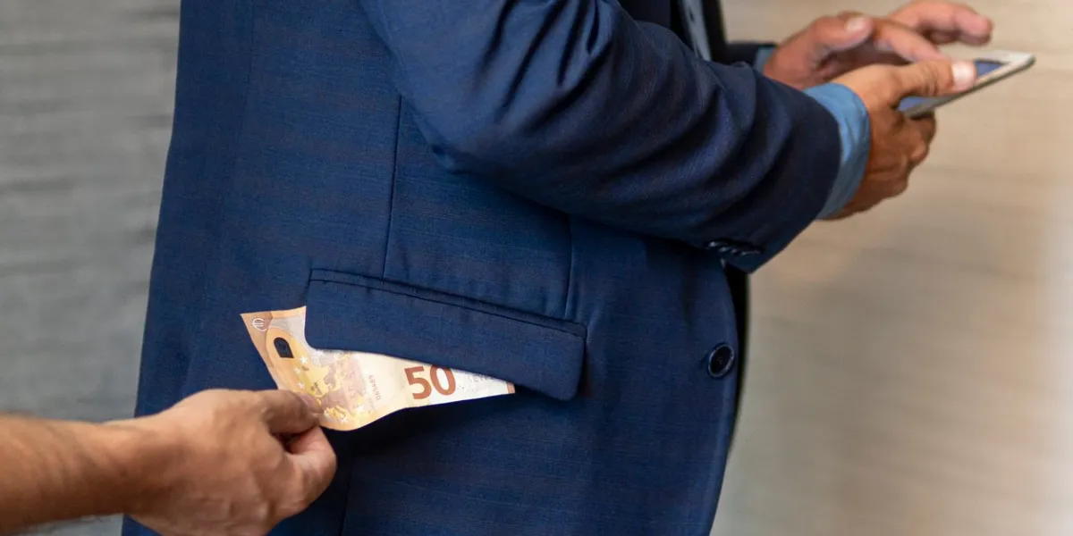 a hand pulls paper money out of his jacket pocket a thief robbed a businessman cash theft, criminal concept