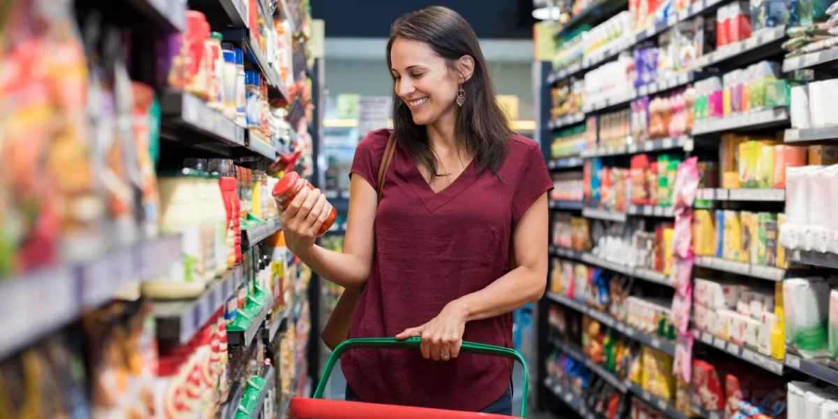 happy mature woman looking at product at grocery store smiling hispanic woman shopping in supermarket and reading product information costumer buying food at the market