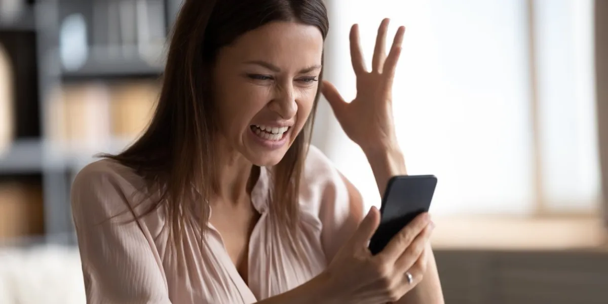 mad young woman look at smartphone screen have operational gadget problems, angry millennial female feel stressed frustrated with slow internet connection, bad service on modern cellphone device