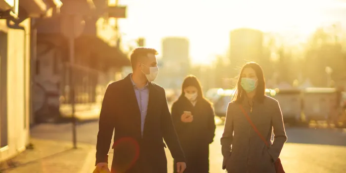 two diverse coworkers walking and chatting two colleagues wearing pollution masks going to a job