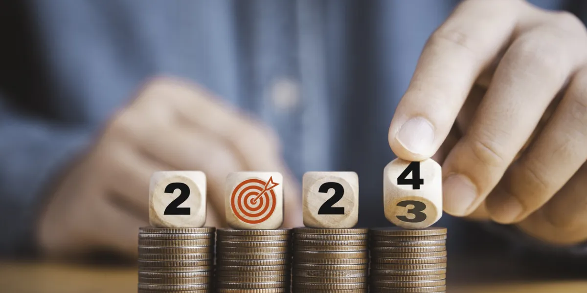 businessman hand flipping wooden block cube from 2023 to 2024 on coins stacking for setup objective target business cost and budget planing of new year concept