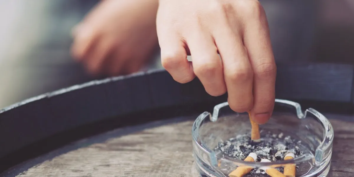 people young man hand putting out a tobacco cigarettes ashtray,cigarette butt on a wooden bucket