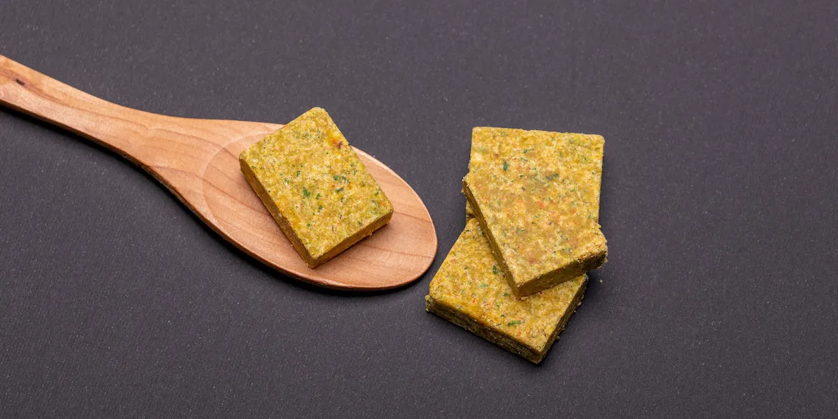 vegetable bouillon stock or broth cube on wooden spoon