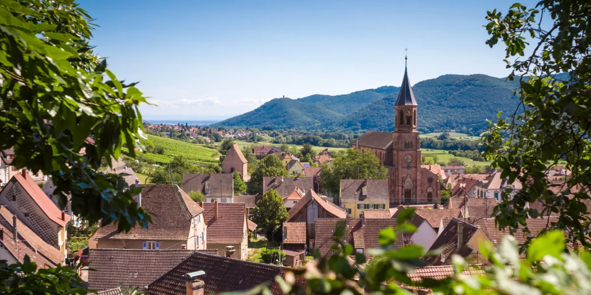 panoramic view of the typical alsatian village wihr-au-val with rooftops, church and hills in the background