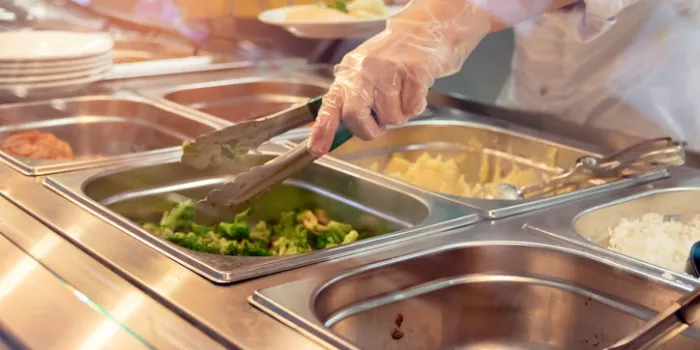 chef standing behind full lunch service station with assortment of food in trays