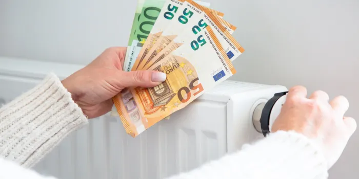 saving home heating, expensive payment for heating radiator and euro money banknotes in woman hands