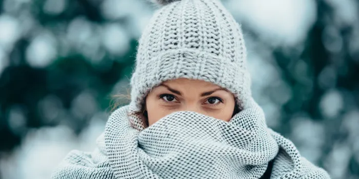 portrait of a beautiful young woman wearing scarf and a a hat on a cold winter day during snow