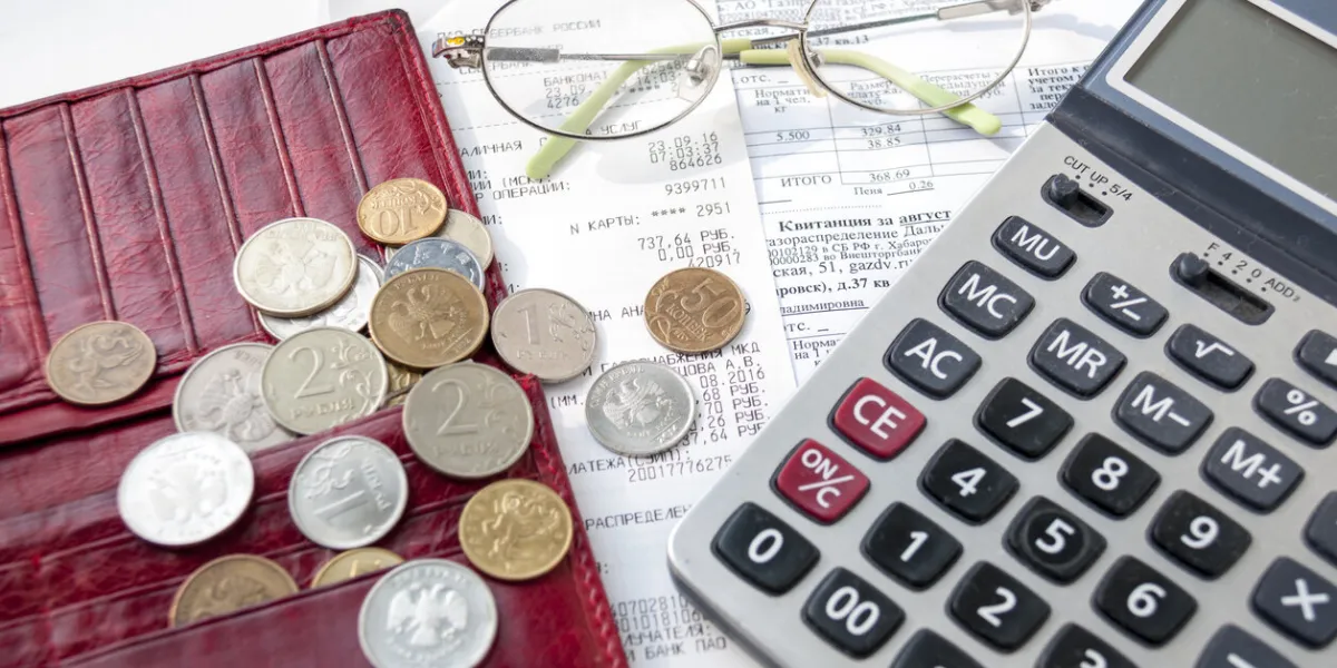 blank red purse, calculator, glasses and money are on the receipts with checks