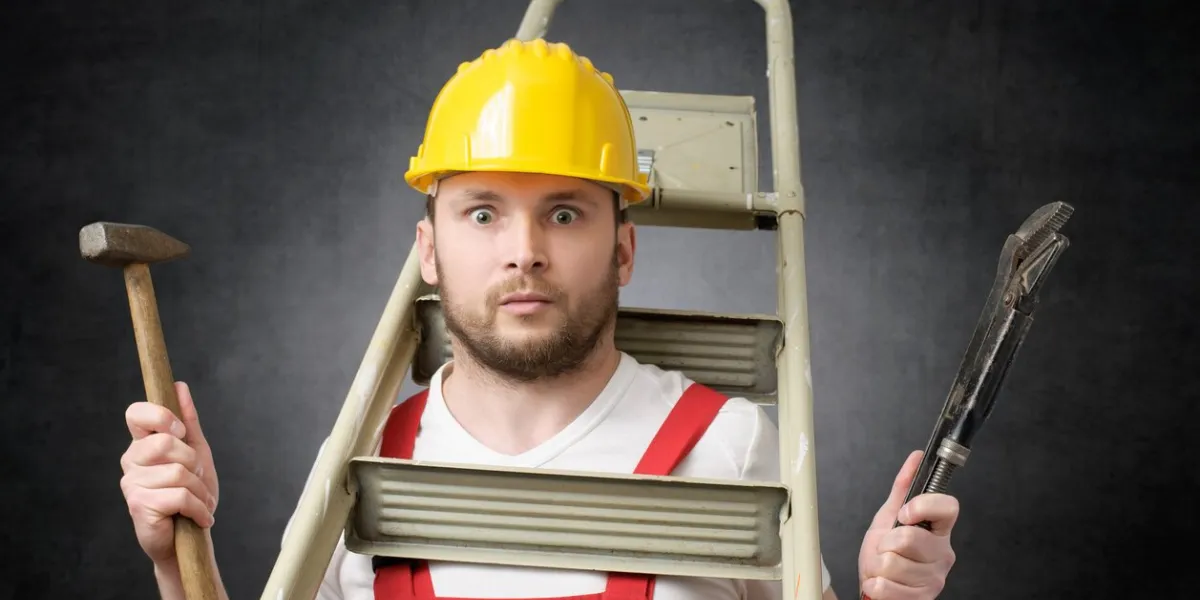 clumsy worker with ladder, hammer and pipe wrench