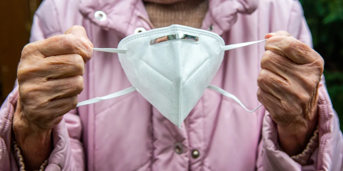 close-up of older womans hands holding face mask