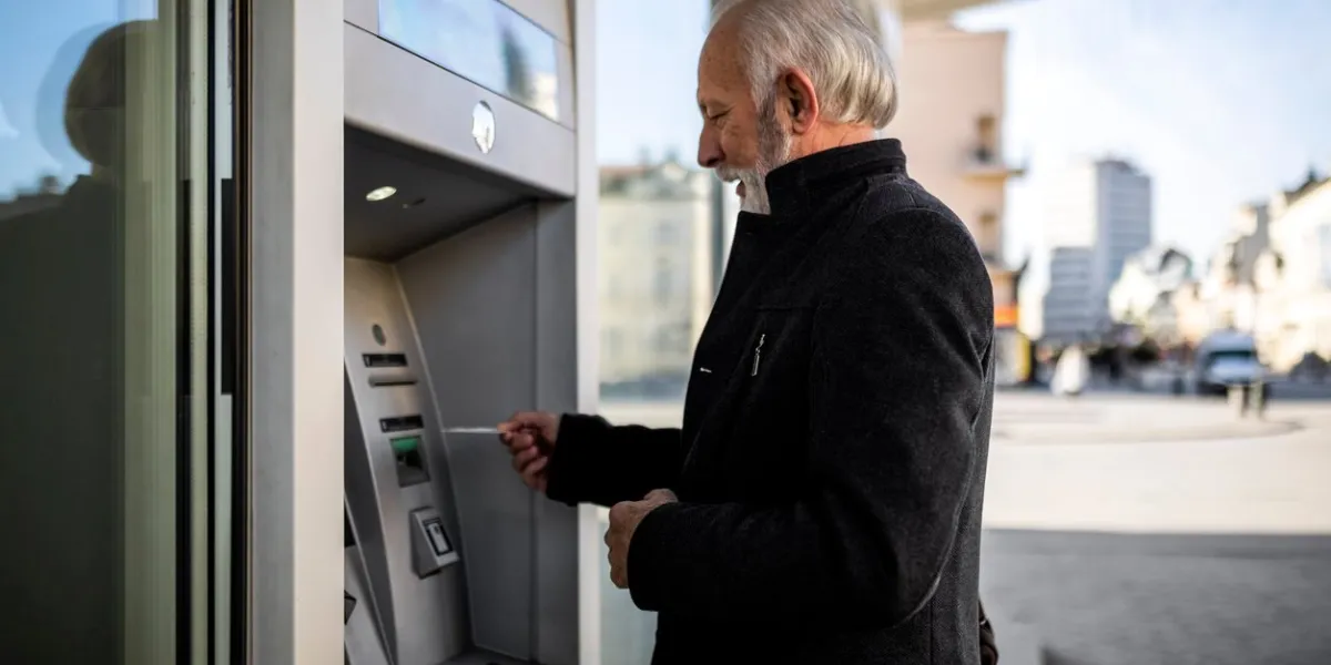 senior businessman inserting a credit card into atm