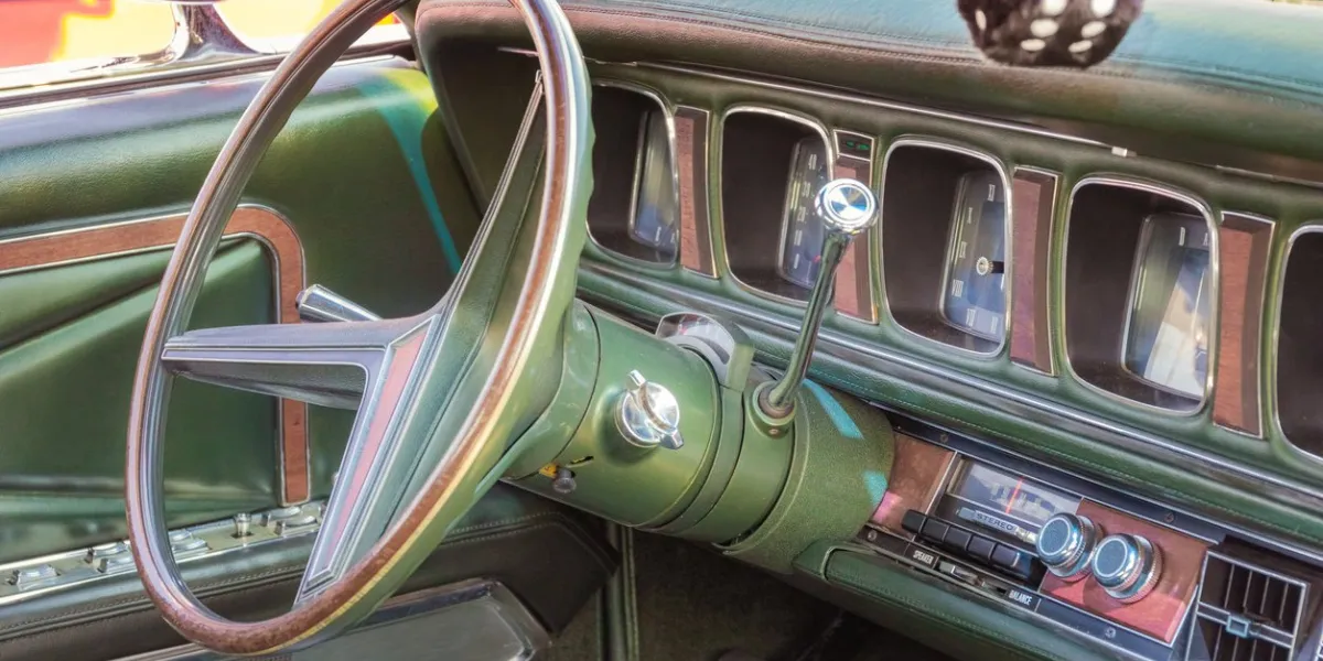 green leather, wood and chrome interior of a classic american luxury oldtimer car steering wheel, radio, speedometer and a hairy dice