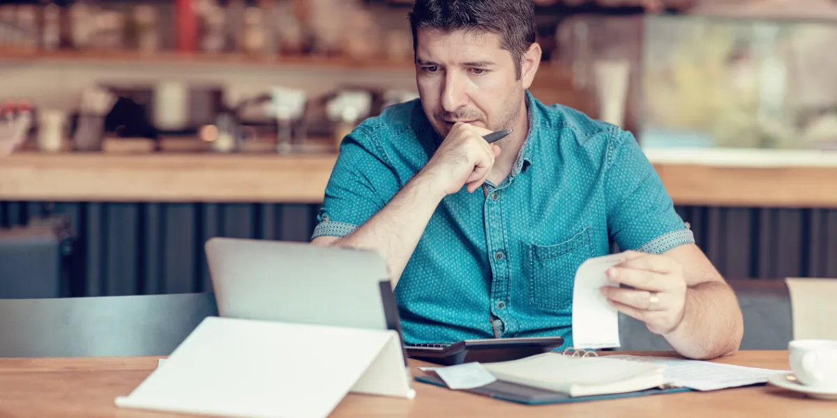 restaurant owner checking monthly reports on a tablet, bills and expenses of his small business