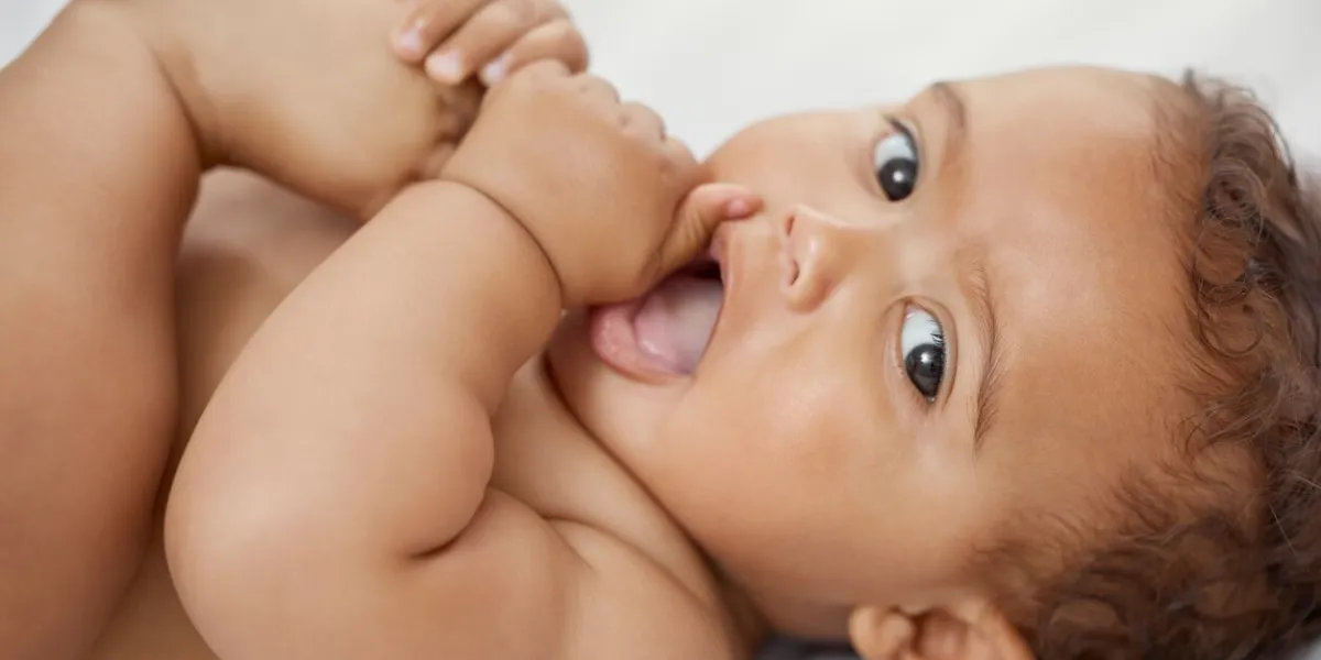 shot of an adorable baby boy lying on the bed and playing with his feet at home