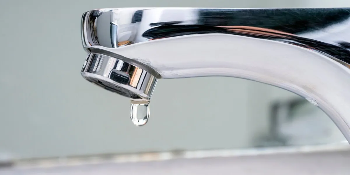 drop of water falling from faucet water supply cuts due to drought severe restrictions measures for water saving increase in prices and taxes on the water bill