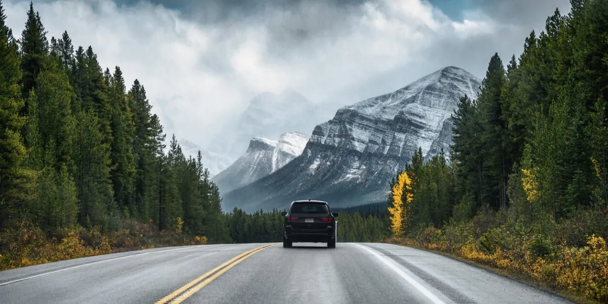 rear of car driving on highway in the forest with mountain on gloomy at banff national park