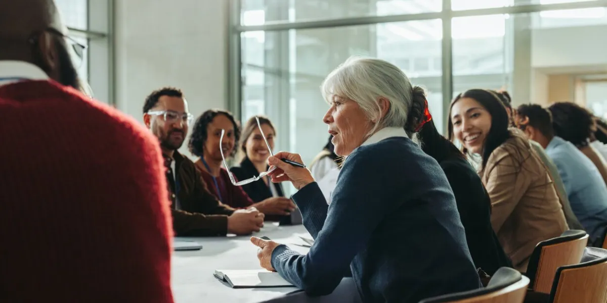 diverse group of business professionals in a meeting with a woman speaking colleagues engage in a collaborative discussion in a modern conference room