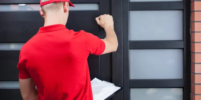 back view of a delivery man knocking on the client's door