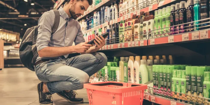 handsome man is choosing cosmetics while doing shopping at the supermarket