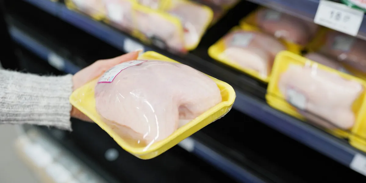 woman choosing packed chicken meat in supermarket