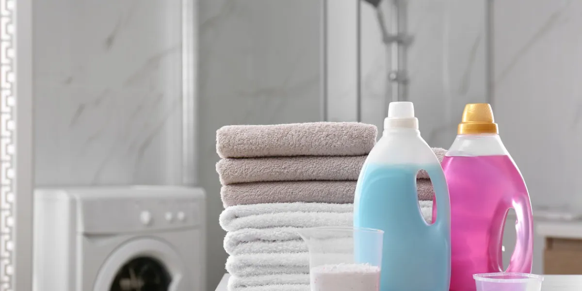 stack of folded towels and detergents on white table in bathroom