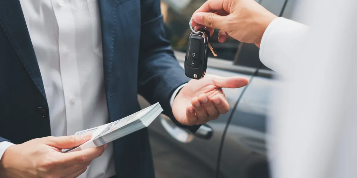 closeup hand giving a car key and money for loan credit financial, lease and rental concept