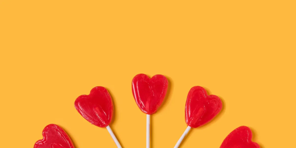 five heart-shaped lollipops on a yellow background love concept valentine day concept top view copy space colorful minimalist style