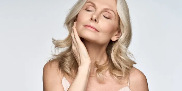 gorgeous senior older woman with closed eyes touching her perfect skin beautiful portrait mid 50s aged woman advertising facial antiage lift products salon care tighten skin isolated on white