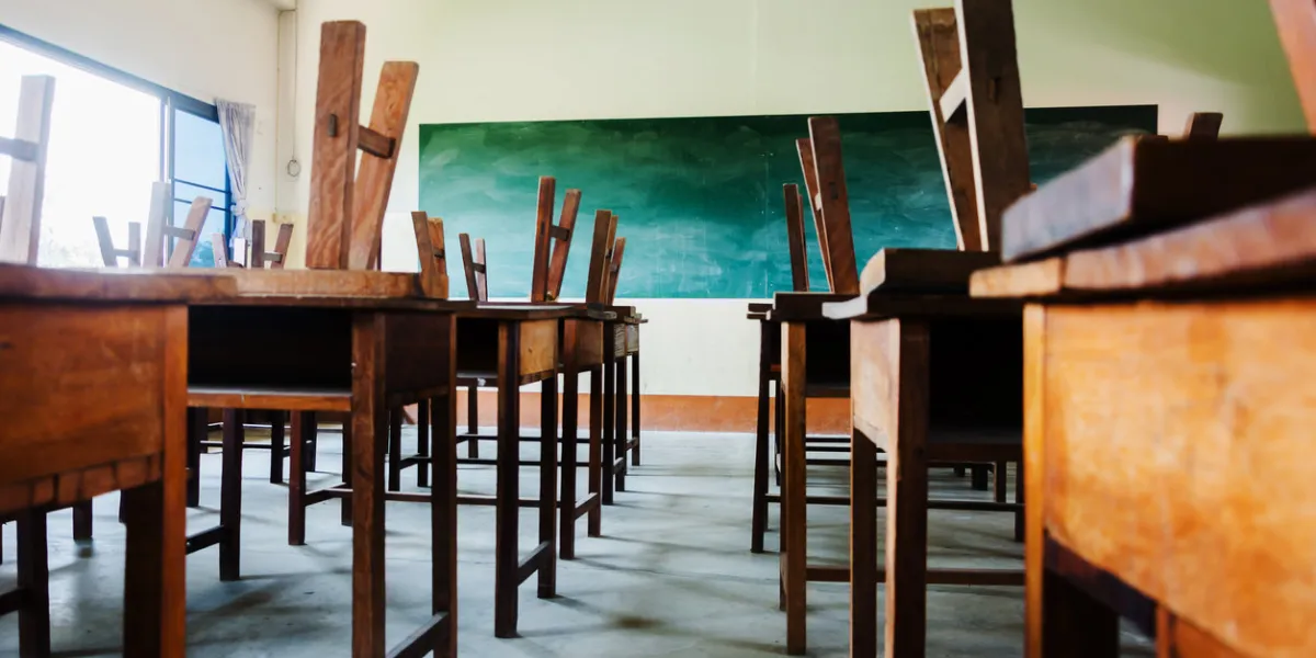 chair and table in class room with black board background, no student, school closed concept