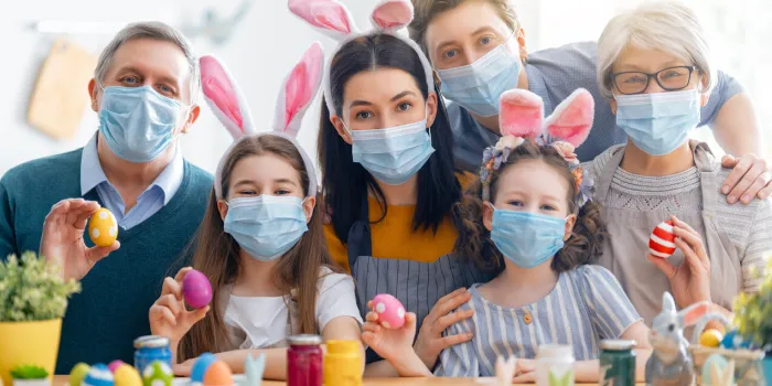 mother, father, grandparents and children are painting eggs happy family are preparing for easter cute little girls wearing bunny ears