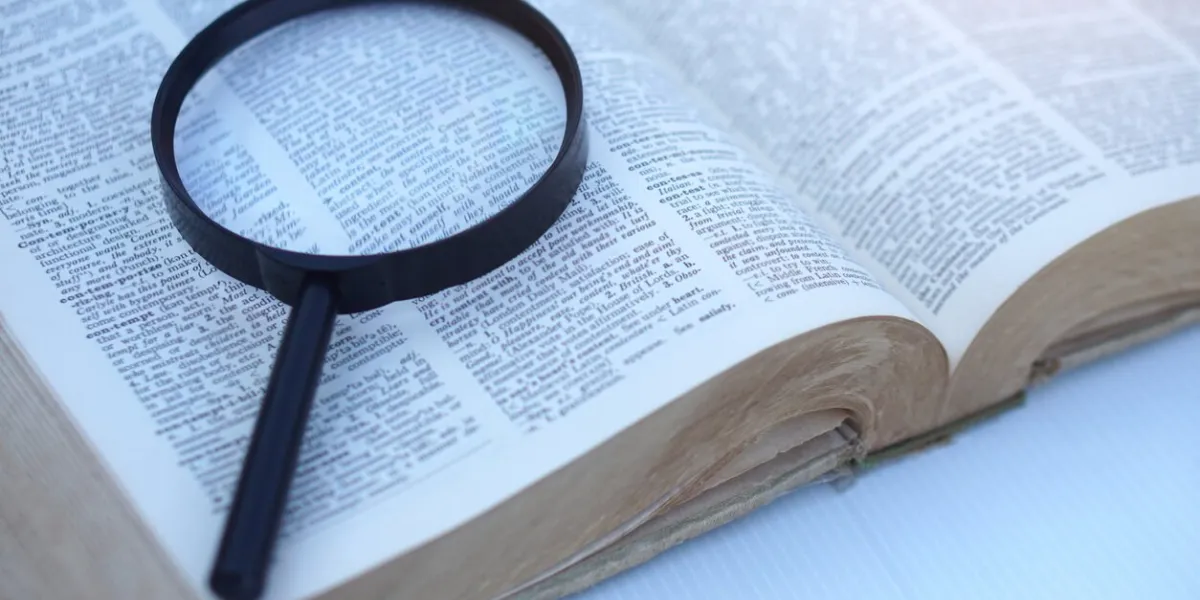 megnifying glass on page of dictionary concept, word searching education