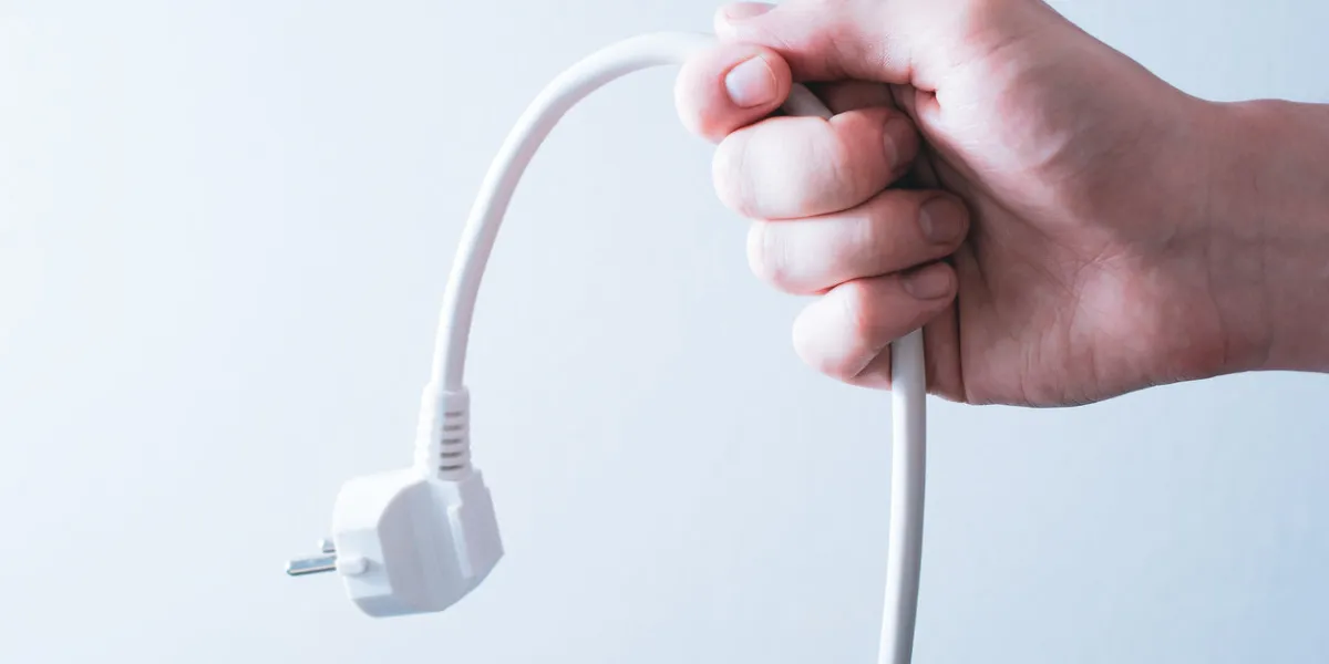 male hand holding a power cable - saving energy concept