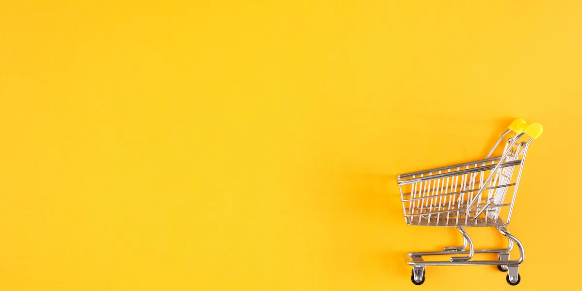 shopaholic buyer shopping concept close-up from above isolated shopping trolley on a yellow background copy space