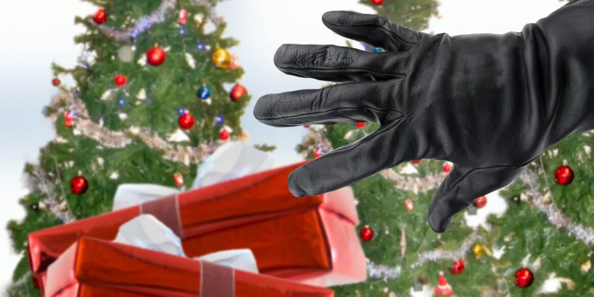 gloved black hand of a thief stealing christmas gifts next the xmas trees