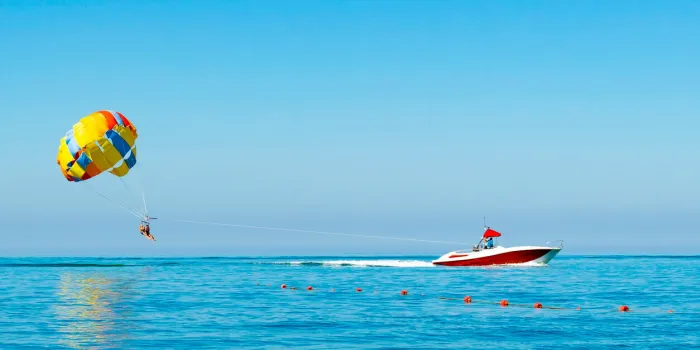parasailing ride on a colored parachute attached to a motor boat place for text