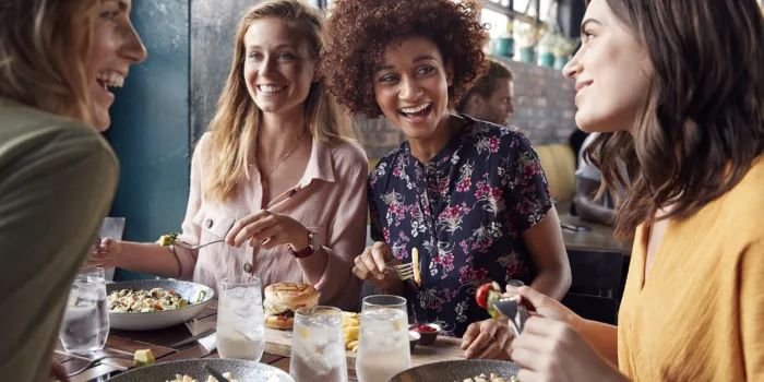 four young female friends meeting for drinks and food making a toast in restaurant