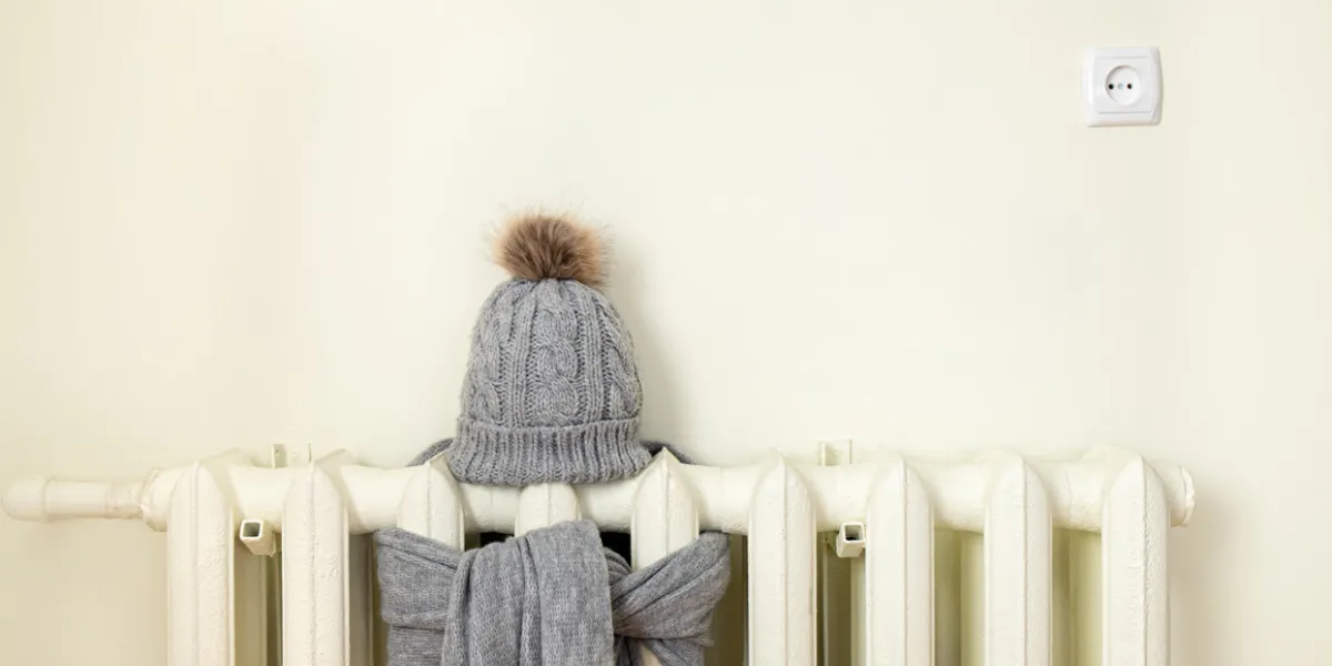 vintage heating radiator with wool knitted winter hat and scarf the electricity and gas bill goes up, european energy crisis concept background copy space, room for text