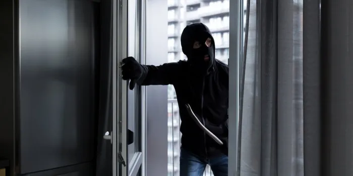 a male thief in a black mask, enters the apartment for robbery, the robber broke the door lock