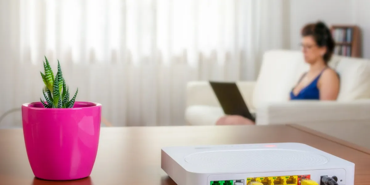 modem router on a table in a living room a woman using a laptop while sitting on the sofa is in background selective focus