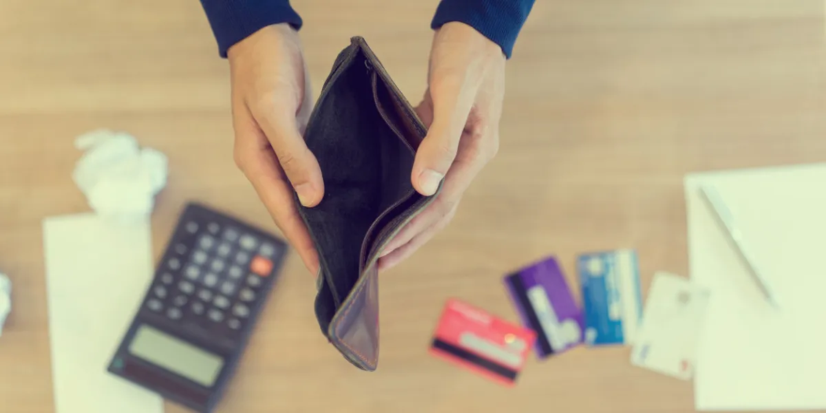 close up man hand opening empty wallet over calculator , debt expense bills monthly and credit card at the table in home office , managing payroll,money risk financial concept