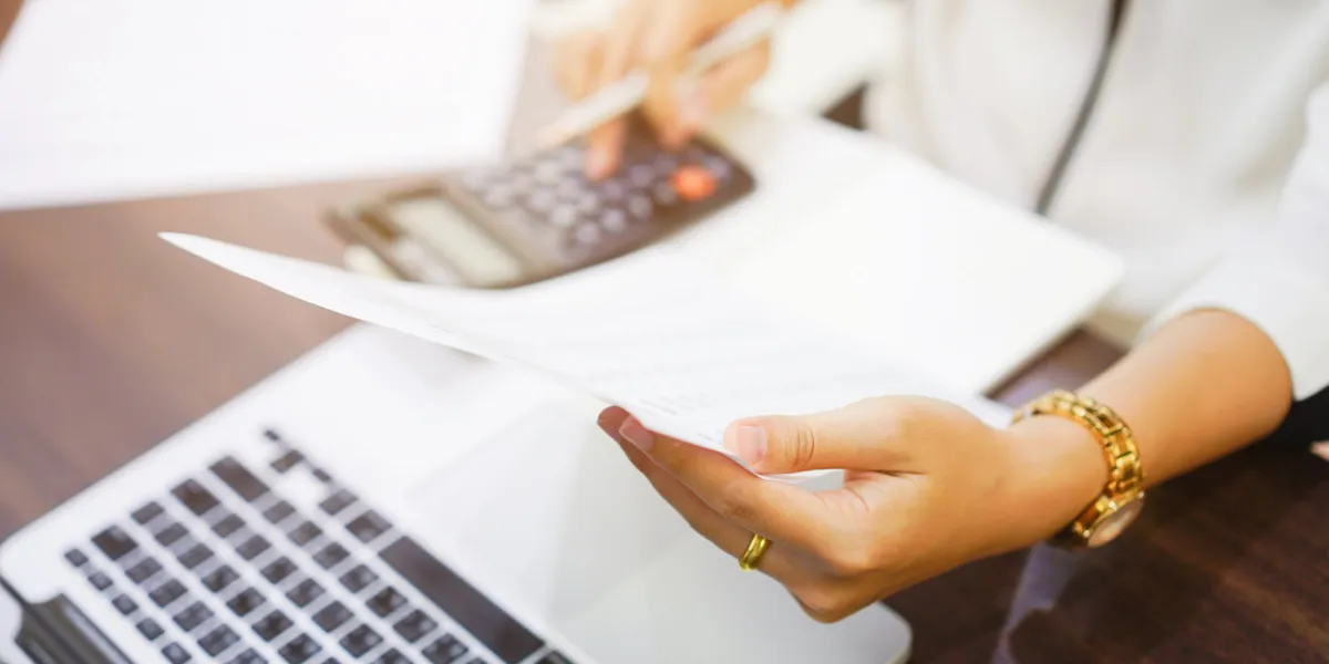 close up on employee woman finger hand holding statement report and press on calculator for summarize company's profit at accounting department ,working woman concept