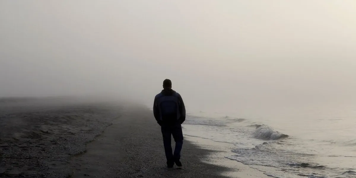 lonely man walking on a foggy beach