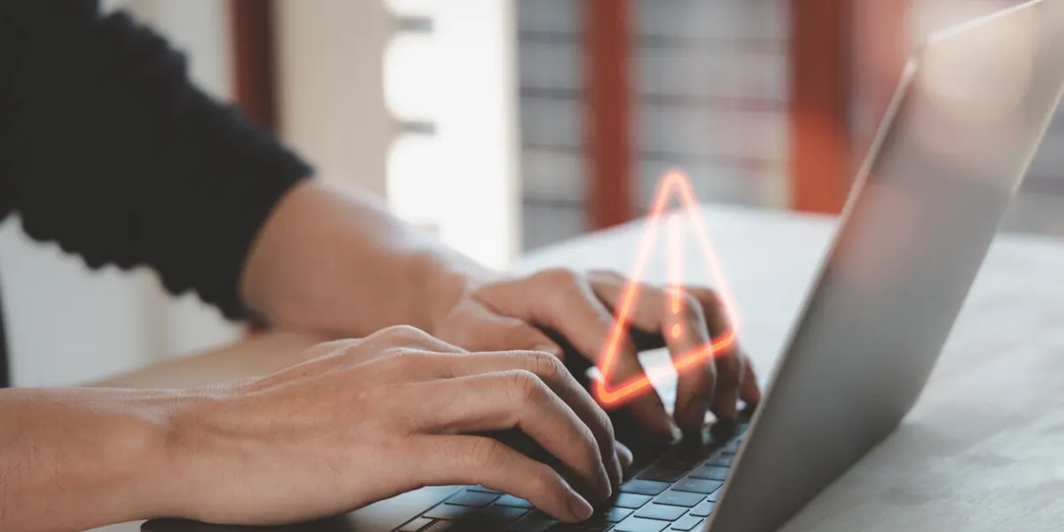 warning hacked alert or it staff , programmer, developer using computer laptop with triangle caution warning sign for notification error and maintenance concept