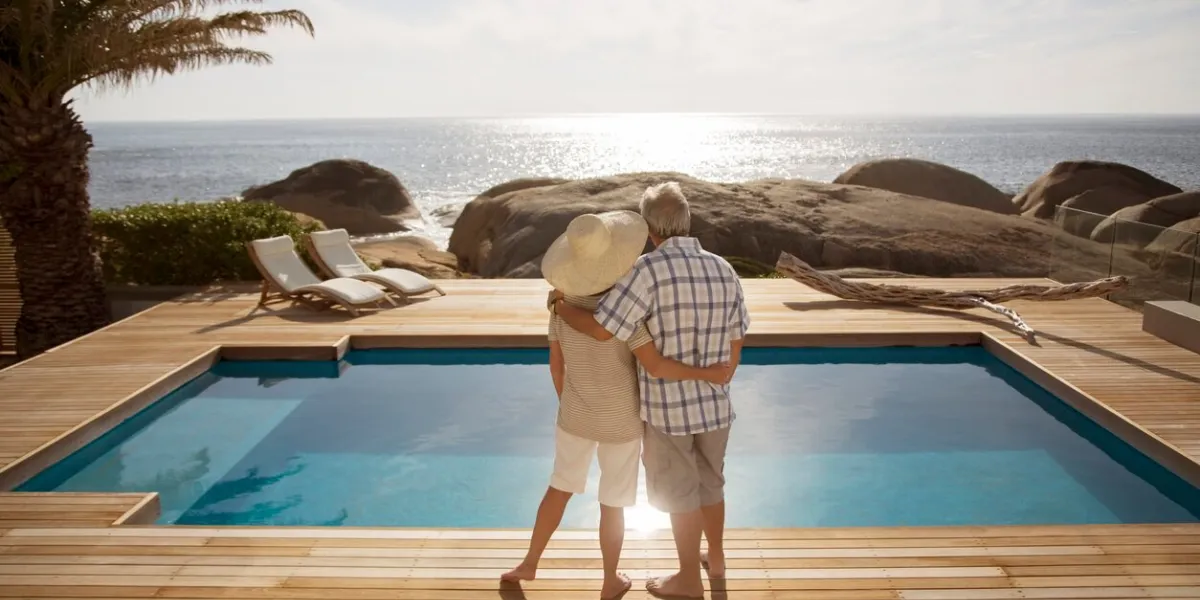 senior couple hugging by modern pool overlooking ocean