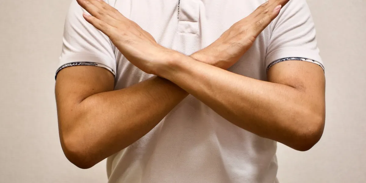 man in white t-shirt made x sign shape mean to say no